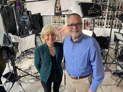 Dr. Greg Jones poses with 60 Minutes correspondent Lesley Stahl in a wine shop with film equipment in background.