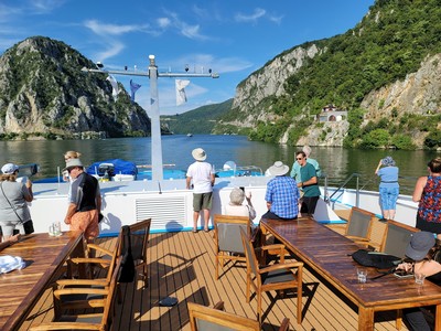 Cruise of southeast europe, boat on river, hills with greenery and rocky outcroppings